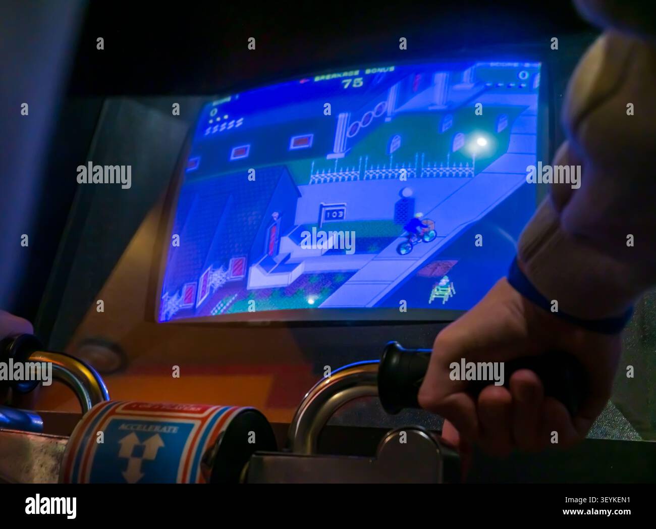 Visitatore che gioca al classico videogioco arcade Paperboy su una macchina arcade originale durante un evento di gioco rétro. Foto Stock