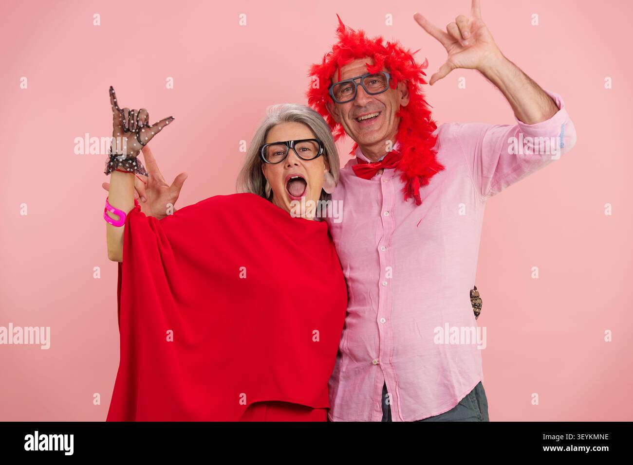 Coppia di anziani sorridenti che si divertono, mostrando gesti della mano rock and roll Foto Stock