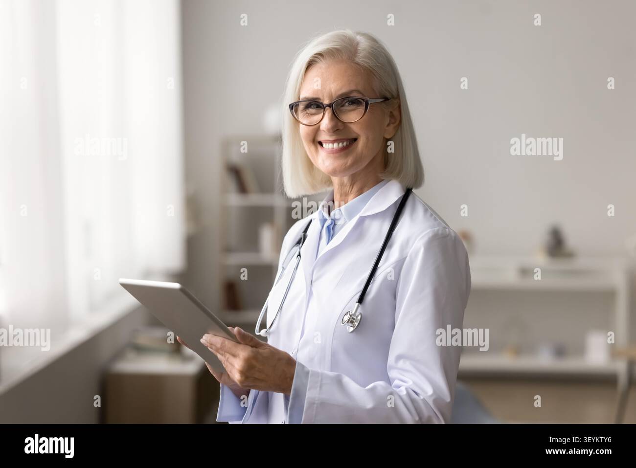 Medico femminile sorridente che guarda la fotocamera che tiene il pc pad Foto Stock