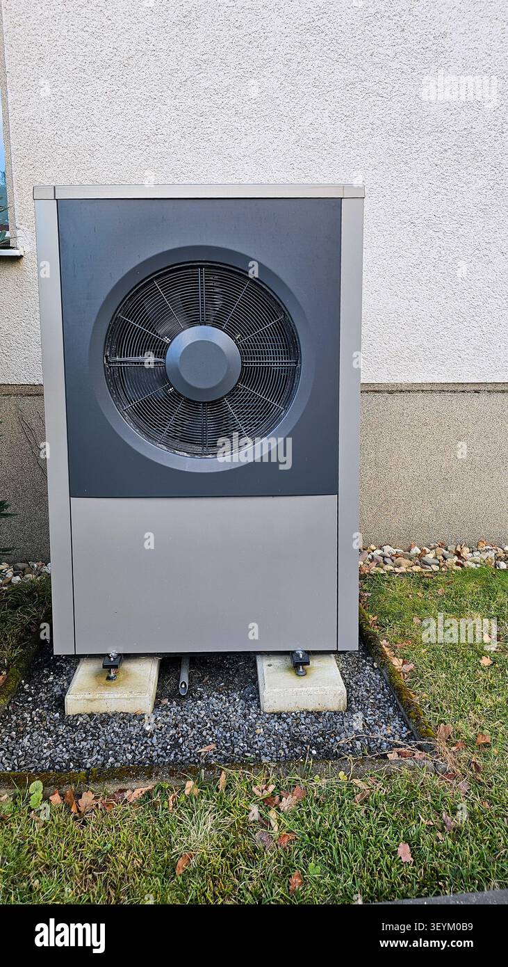 Moderna unità pompa di calore a sorgente d'aria installata all'aperto su una parete della casa, che offre un controllo della temperatura sostenibile Foto Stock