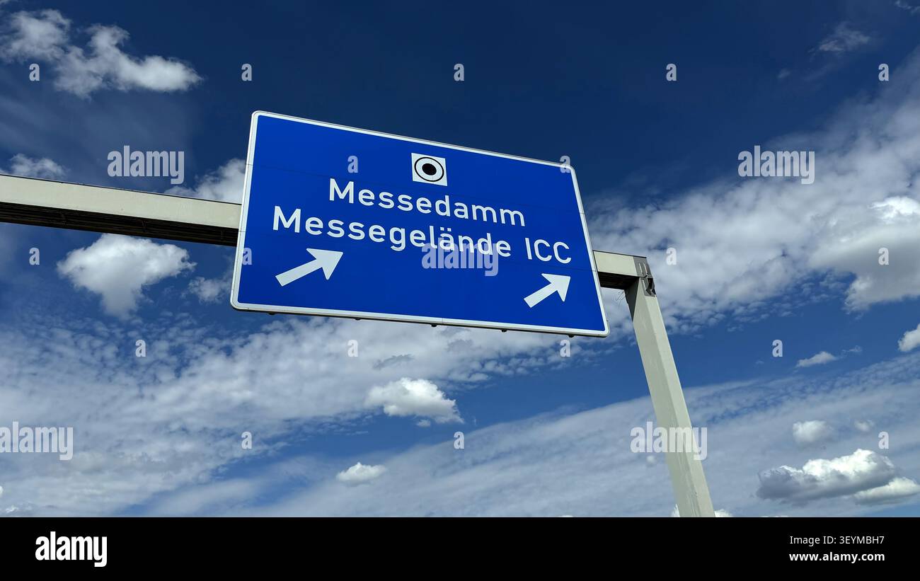 Cartello stradale direzionale che indica Messedamm e Messegelande con frecce che puntano a sinistra e a destra contro un cielo blu con nuvole Foto Stock
