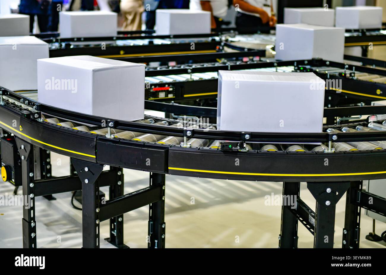 Sistema automatizzato di nastri trasportatori che trasporta scatole di cartone bianco vuote in un moderno centro logistico di adempimento Foto Stock