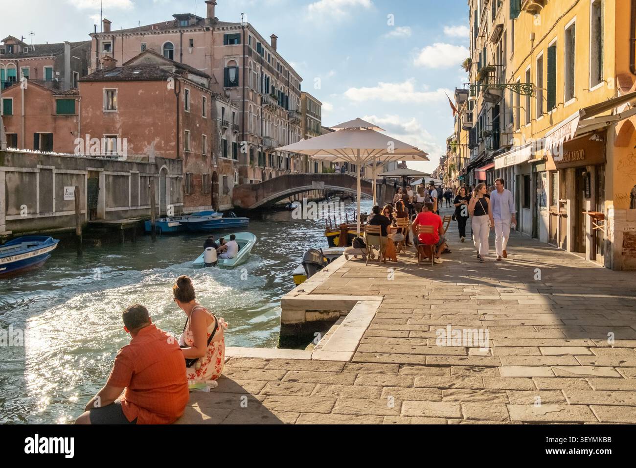 Persone che si rilassano e mangiano vicino a un canale panoramico a Venezia, Italia Foto Stock