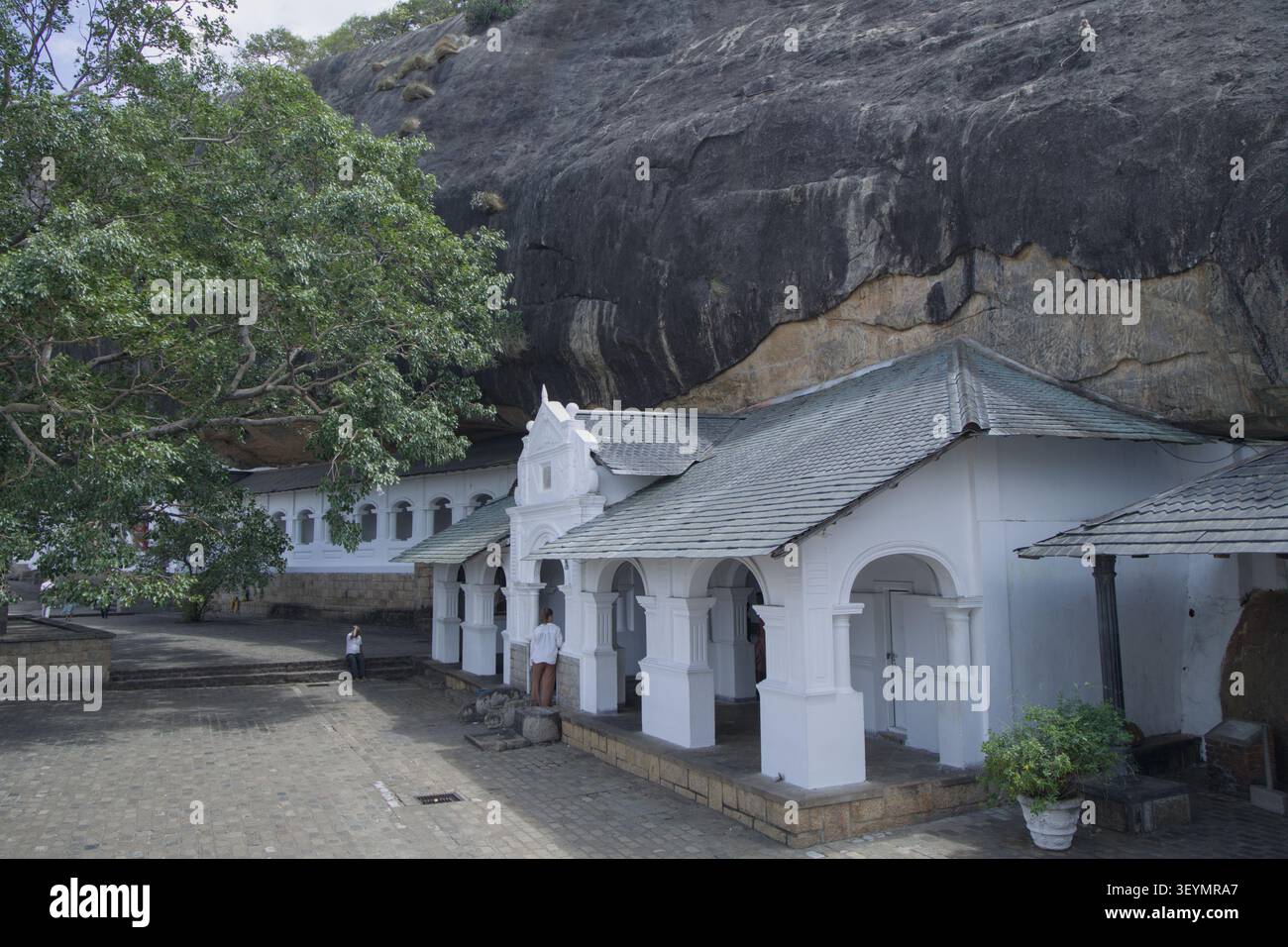 Edifici con templi bianchi e strutture monastiche ai piedi della massiccia roccia di granito del Tempio della grotta di Dambulla nella provincia centrale dello Sri Lanka. Le Nazioni Unite Foto Stock