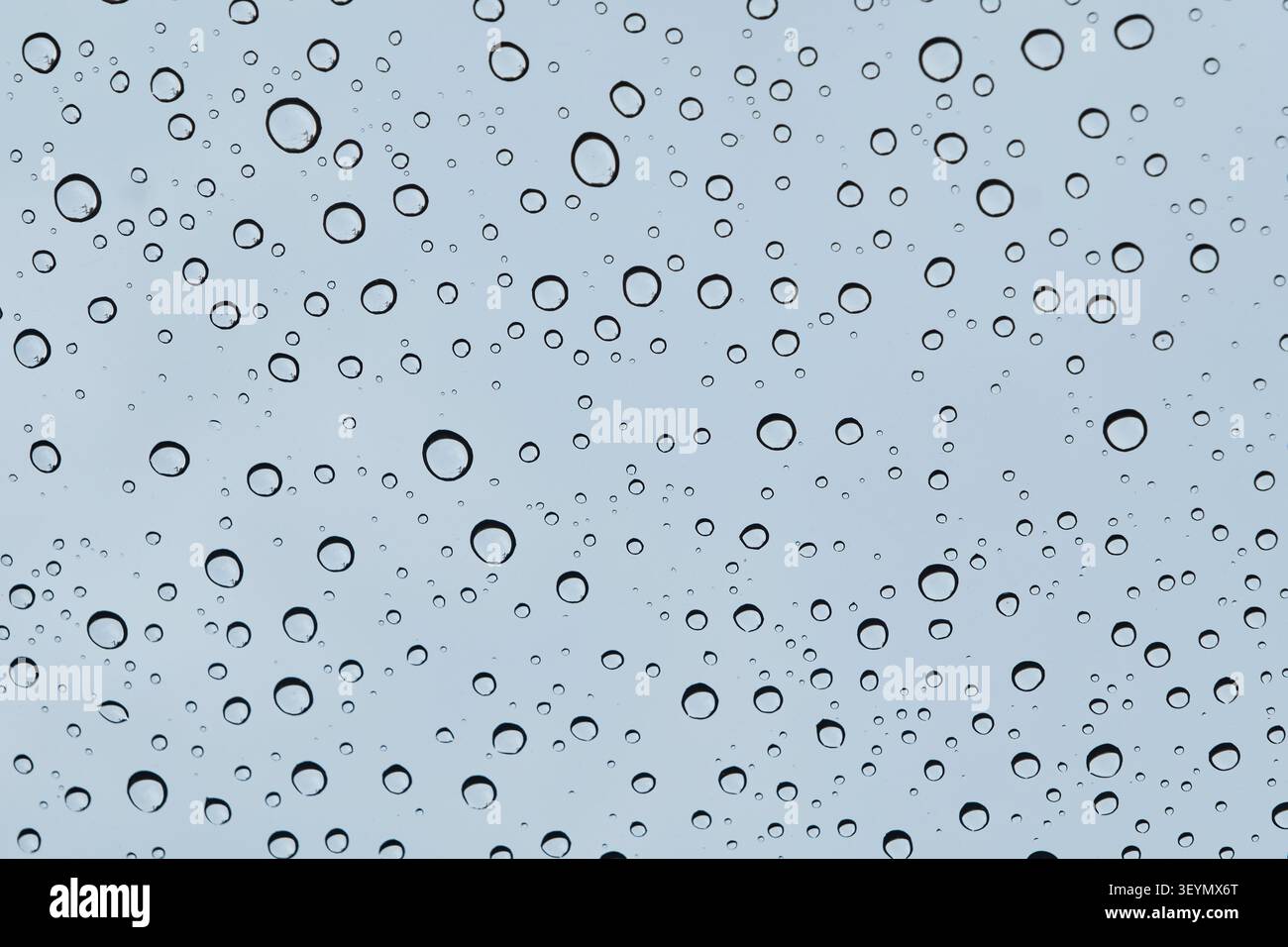 molte gocce di pioggia sul parabrezza dell'auto nel cielo blu nuvoloso Foto Stock