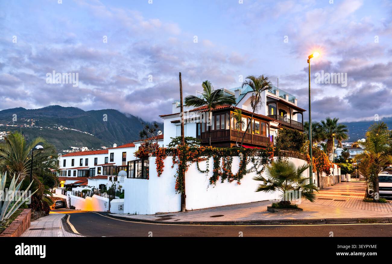 Tradizionali edifici bianchi con balconi in legno e palme al crepuscolo a Puerto de la Cruz, Tenerife, Isole Canarie, Spagna. Foto Stock
