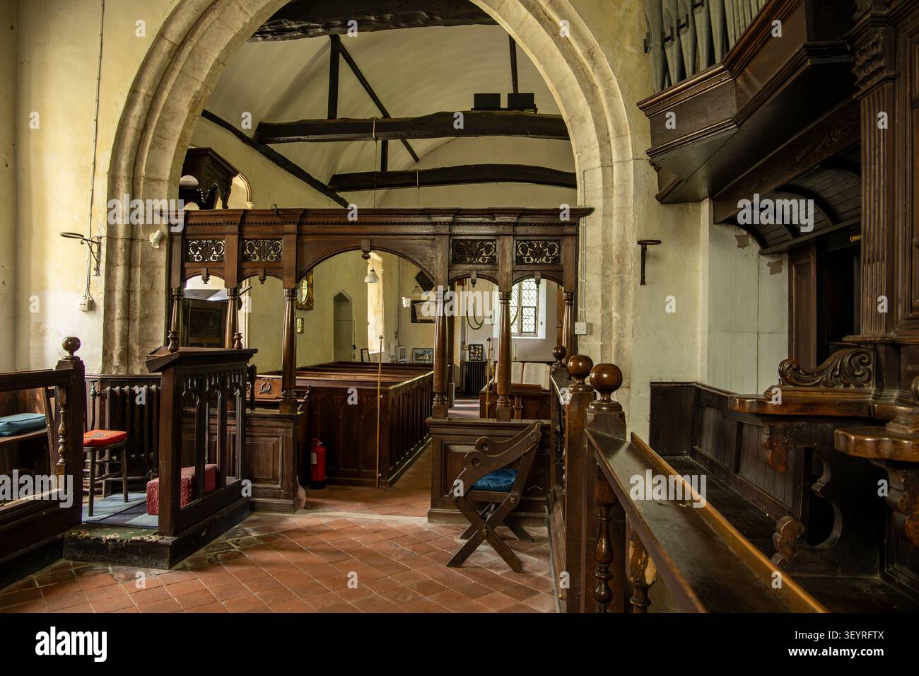 Vista interna di una vecchia chiesa parrocchiale con un tramezzo in legno, travi in legno, archi in pietra e banchi tradizionali Chiesa di San Nicola Leckford Foto Stock
