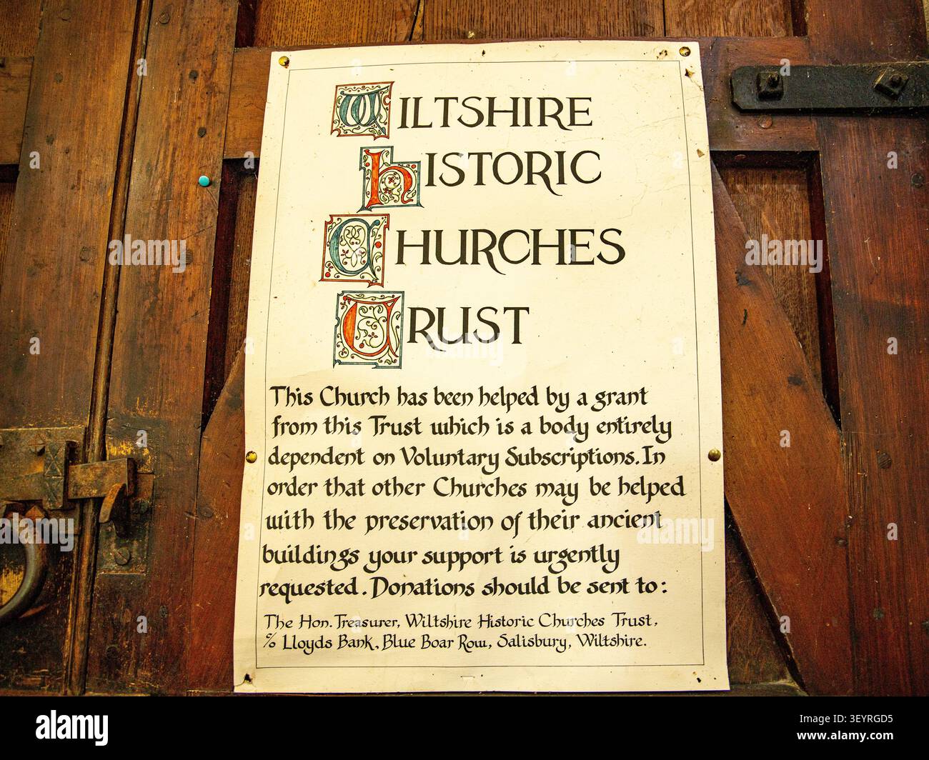 Un cartello del Wiltshire Historic Churches Trust displayed su una porta di chiesa in legno rustico nella chiesa di Santa Maria a Collingbourne Kingston Foto Stock