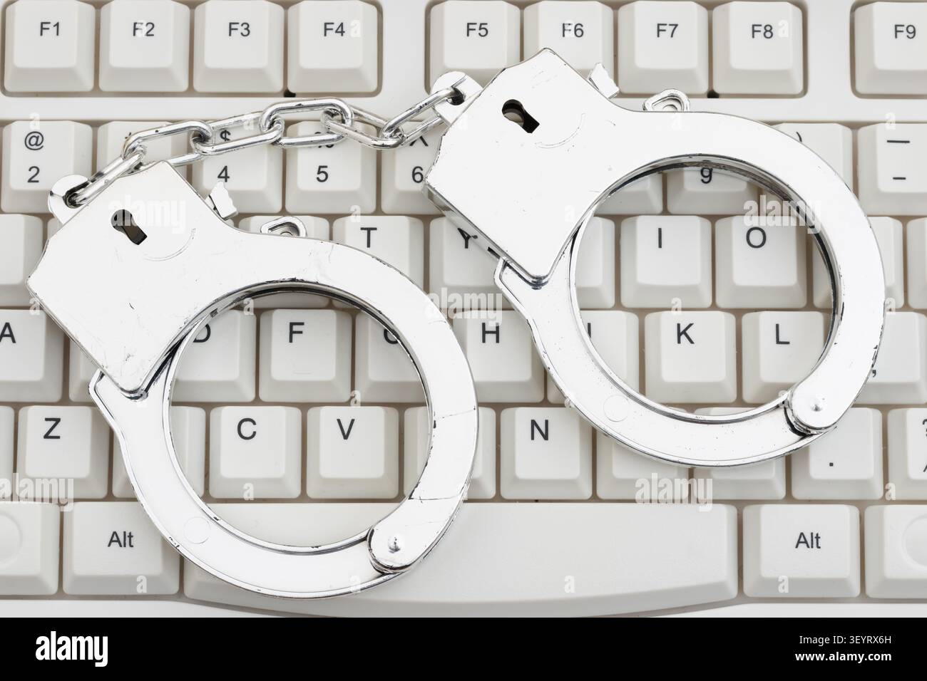 Manette su una tastiera bianca per computer per prove forensi per computer in caso di furto di identità, Foto Stock