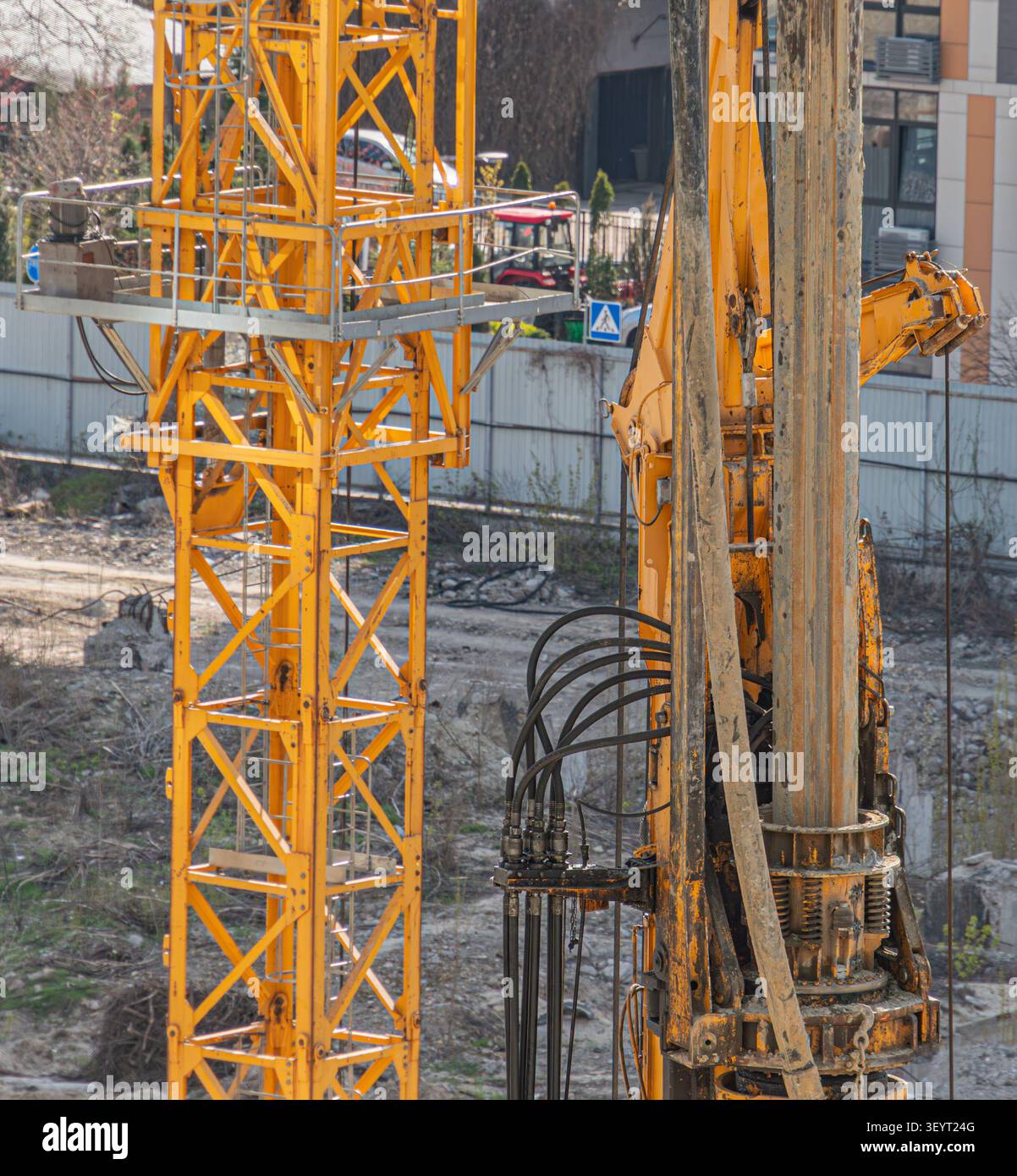 Attrezzature per l'edilizia pesante, carro di perforazione operativo in cantiere attivo, contesto di sviluppo urbano, trattore rosso visibile, struttura di base stabile, moder Foto Stock