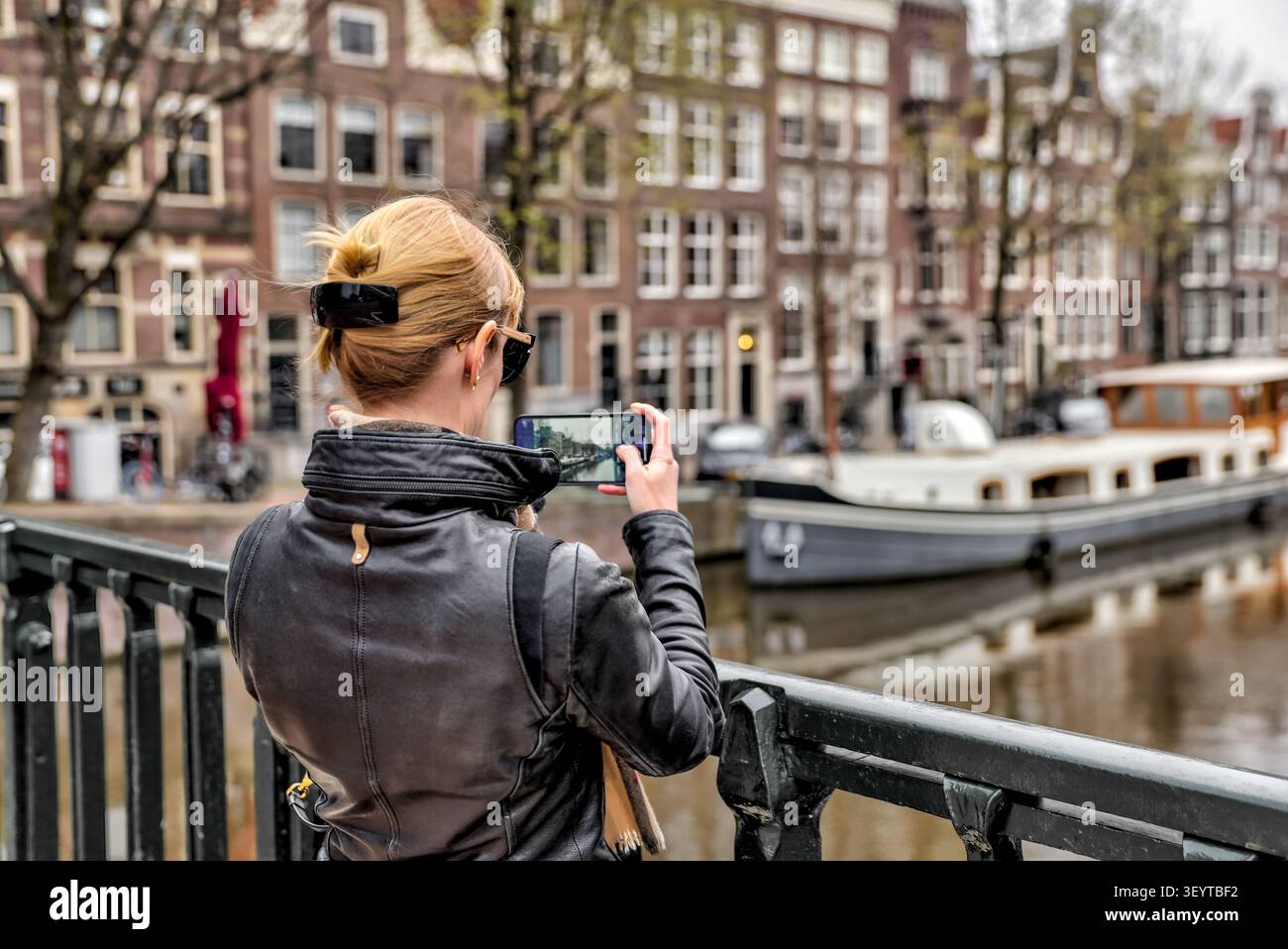 Turista che fotografa uno dei canali storici di Amsterdam nei Paesi Bassi. Foto Stock