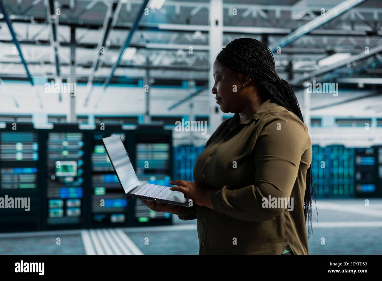 Donna in una struttura server che conduce test sull'infrastruttura che lavora con software per correggere i bug. Foto Stock