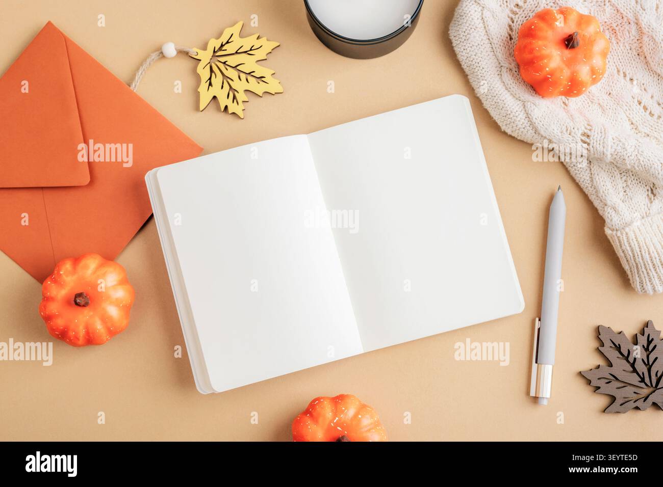 Quaderno aperto con decorazioni autunnali, zucche, candela e maglione accogliente. Vista dall'alto composizione stagionale con spazio per le copie, disposizione piatta. Foto Stock
