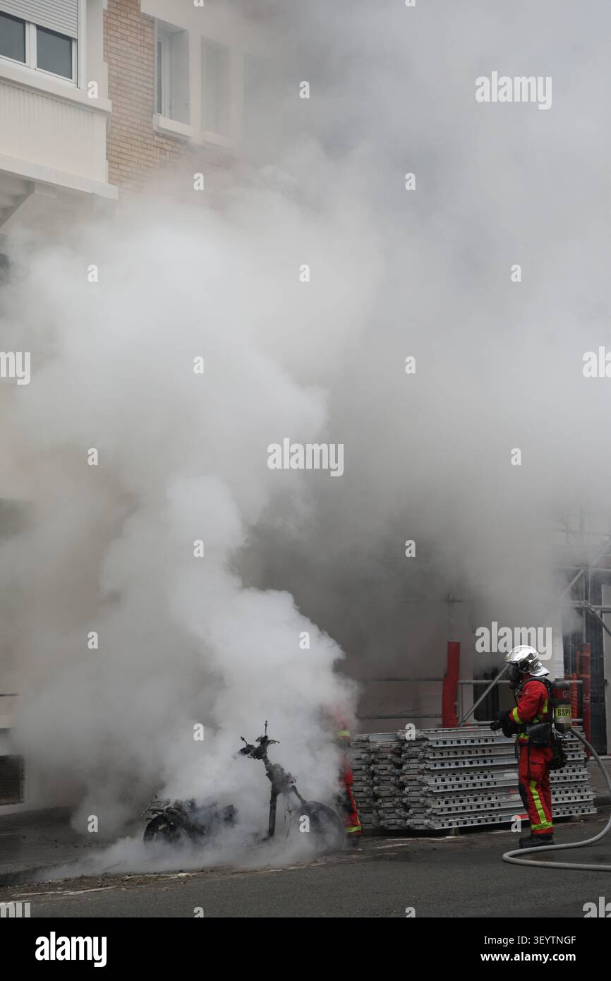 Un pompier éteint un feu avec de la fumée. Foto Stock