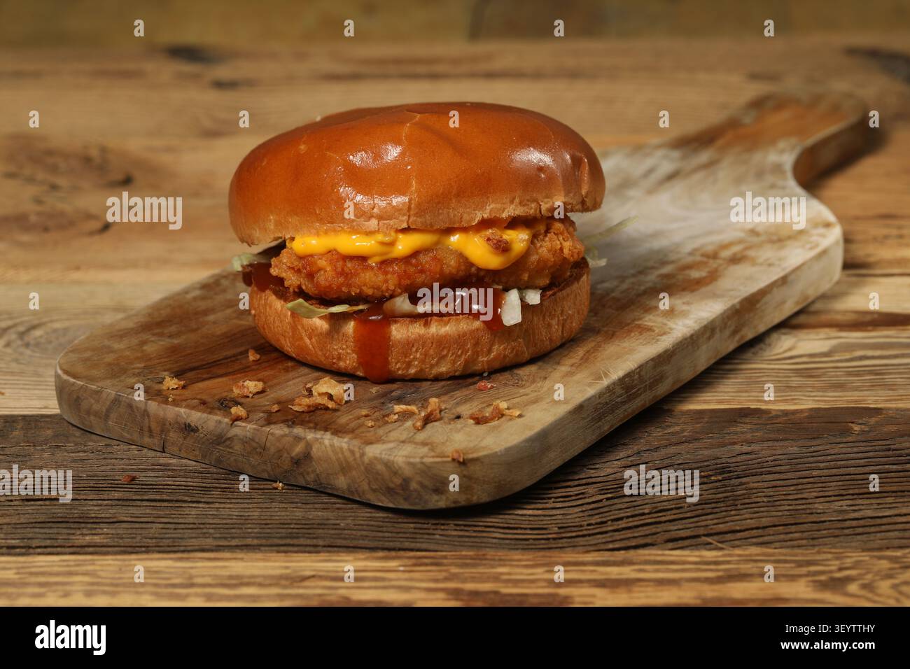 Un hamburger posé sur une planche en bois. Foto Stock