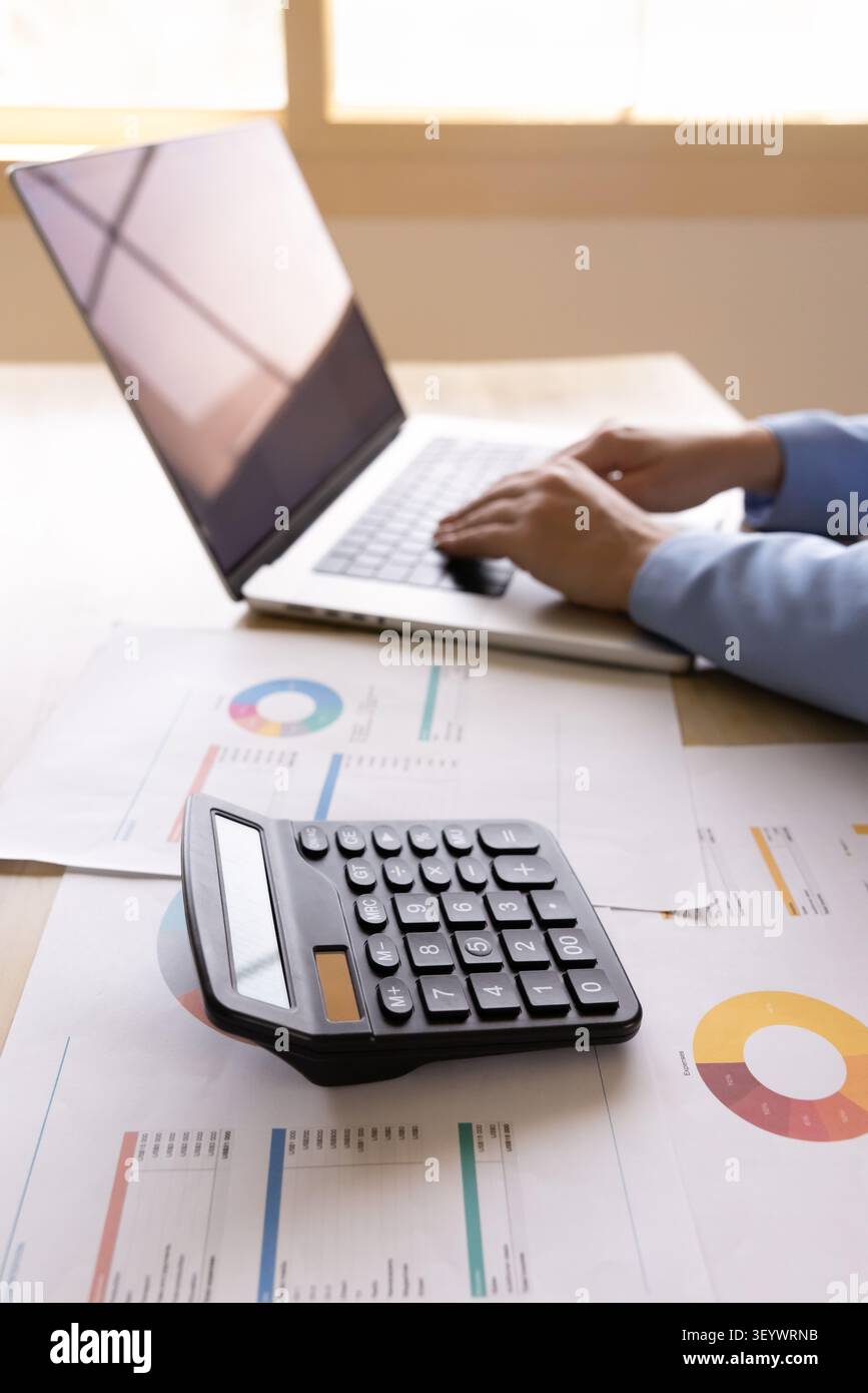 Contabile donna che scrive su un computer portatile alla scrivania con documenti finanziari Foto Stock