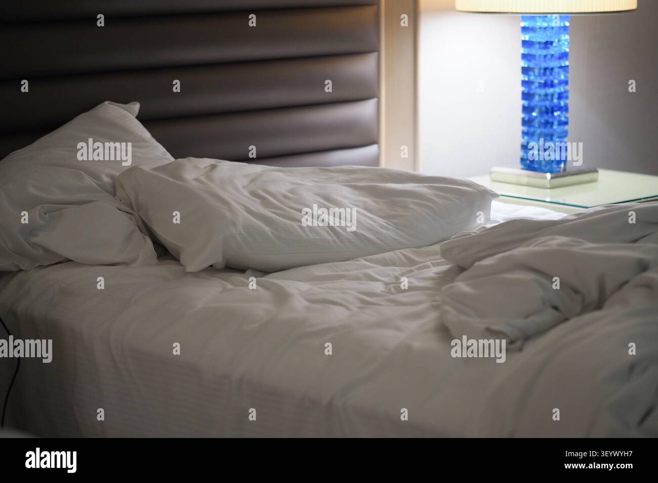Letto con lenzuola e cuscini disordinati in camera di notte Foto Stock