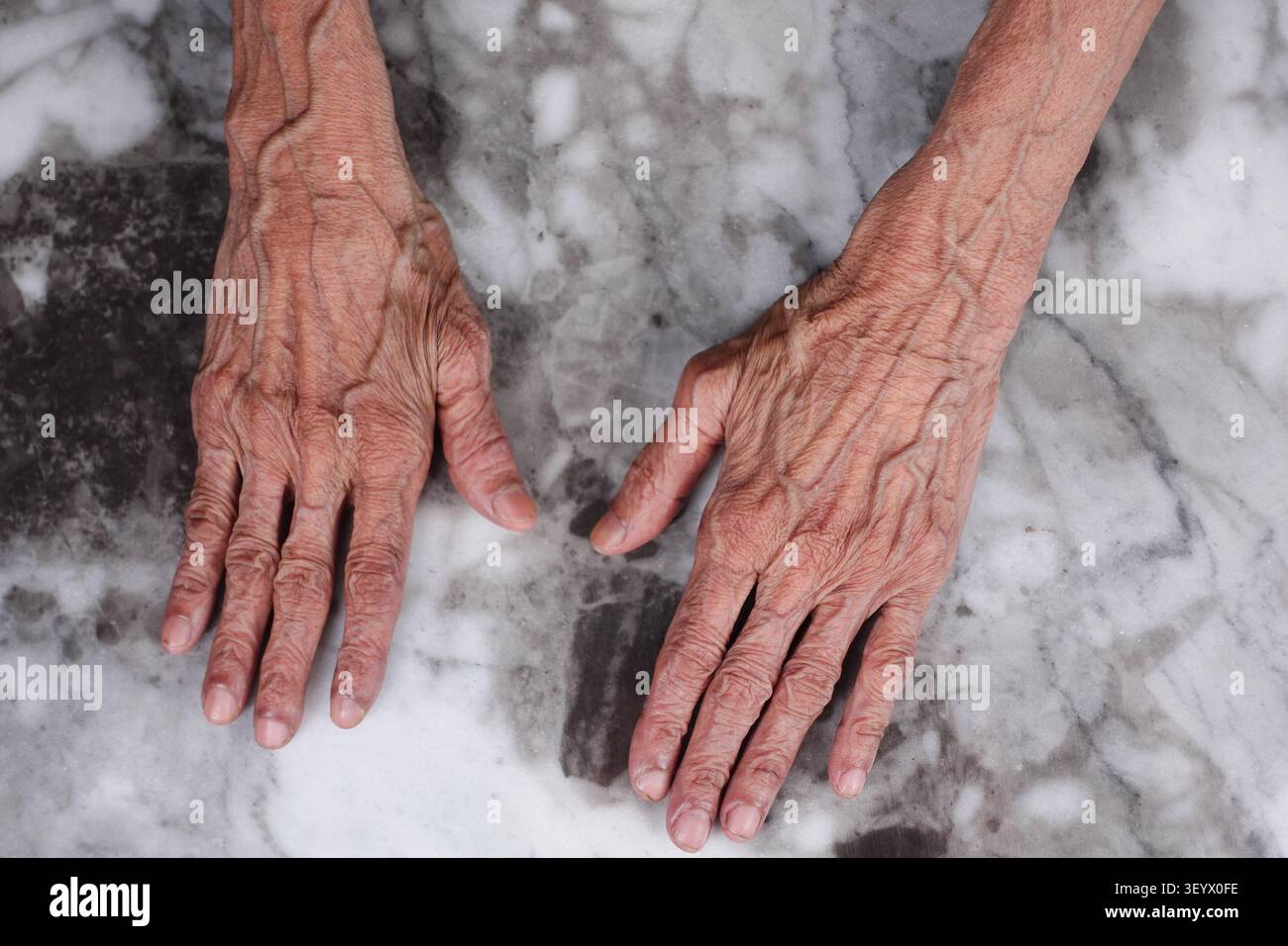 Mani appoggiate su una superficie di marmo in un ambiente semplice Foto Stock