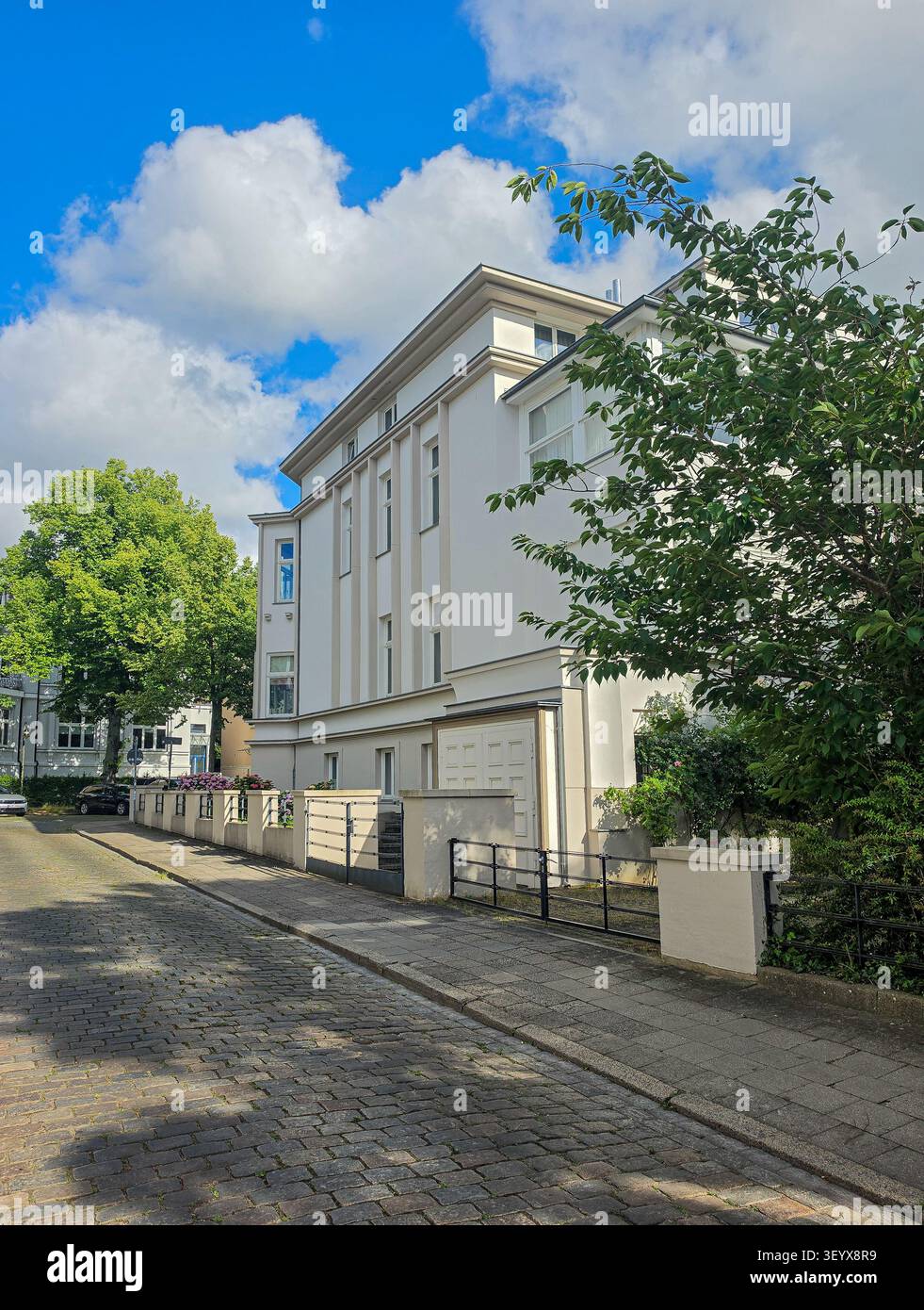 edificio residenziale bianco moderno con architettura elegante su una strada suburbana soleggiata Foto Stock