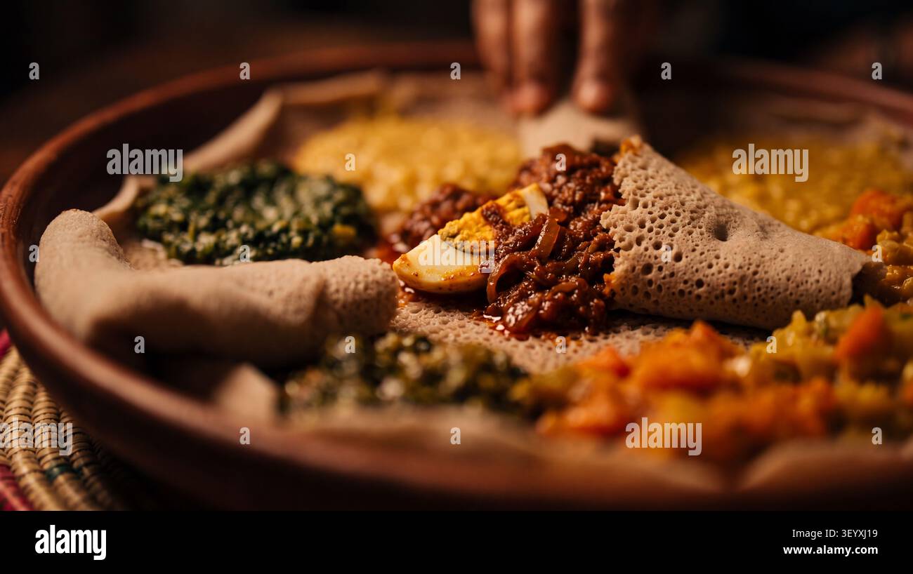 Autentico injera etiope servito con Doro Wat, uno stufato di pollo speziato con miscela di spezie berbere, cipolle, aglio e uova sode. Il grande fermento Foto Stock