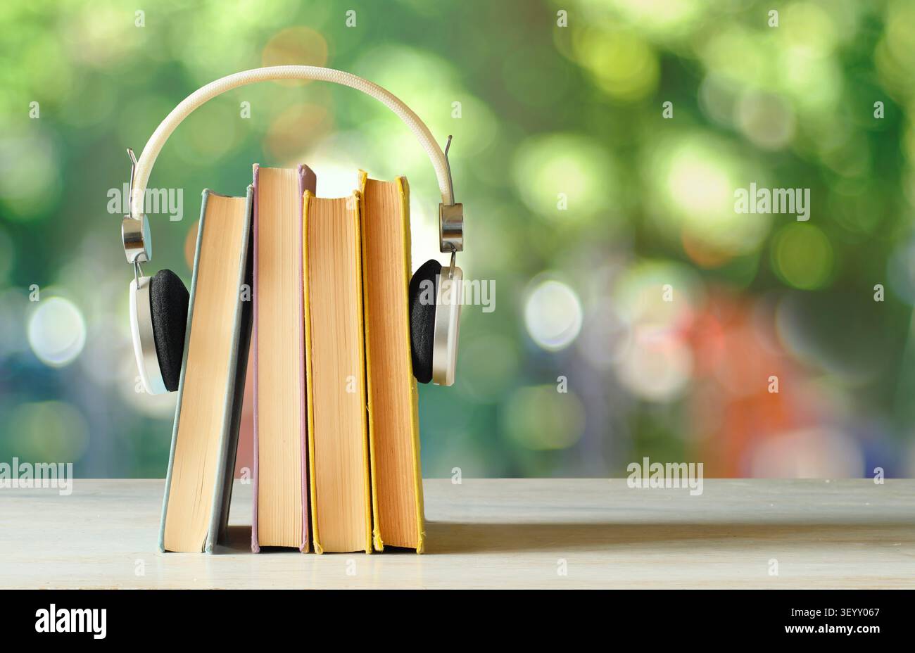 Concetto di audiolibri con una pila di libri e cuffie, sfondo sfocato e morbido. Foto Stock