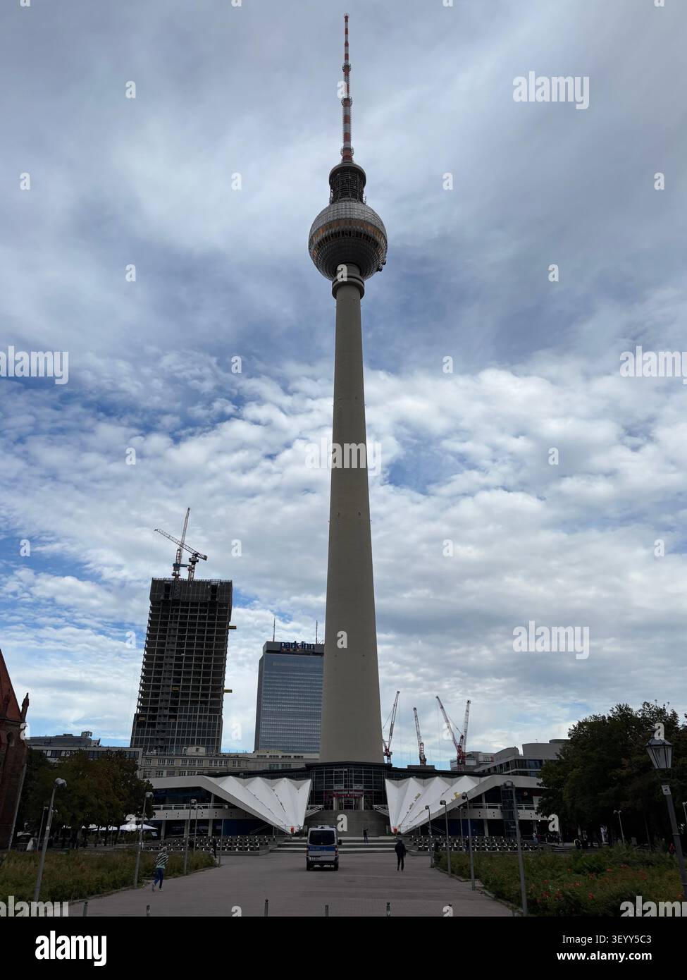 Vista ad angolo basso della famosa Torre della Televisione di Berlino (Fernsehturm) ad Alexanderplatz sotto un drammatico cielo nuvoloso, Berlino, Germania - Immagine stock catturata con smartphone