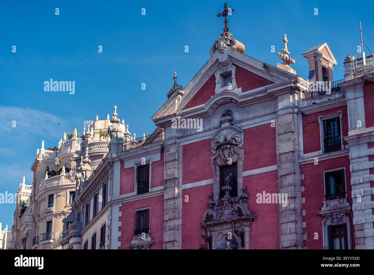 Facciata di chiesa storica in mattoni rossi accanto ad architettura elegante sulla Gran Via a Madrid, Spagna Foto Stock