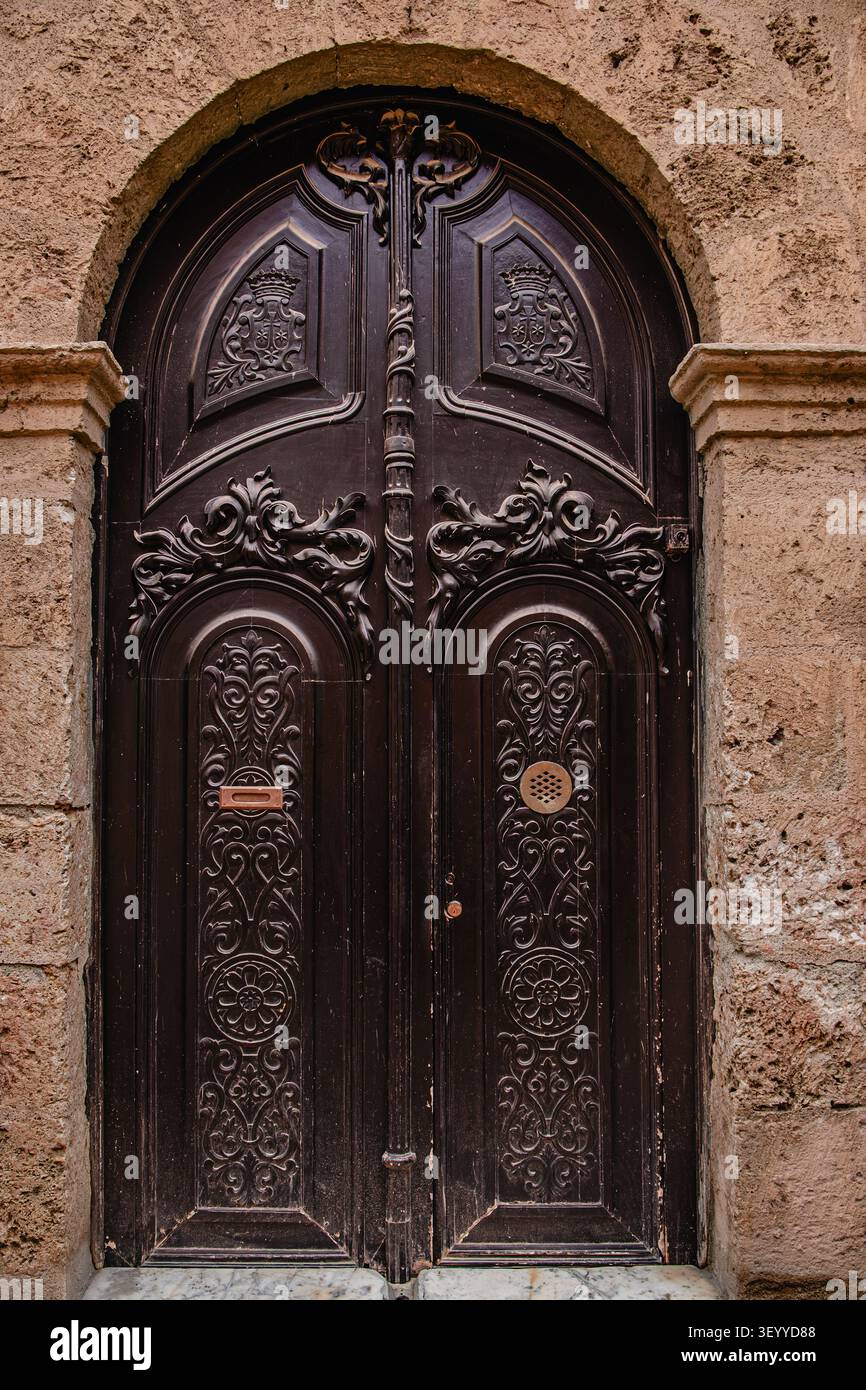 Intricata porta di legno con intagli ornati in un edificio storico da una strada pittoresca Foto Stock