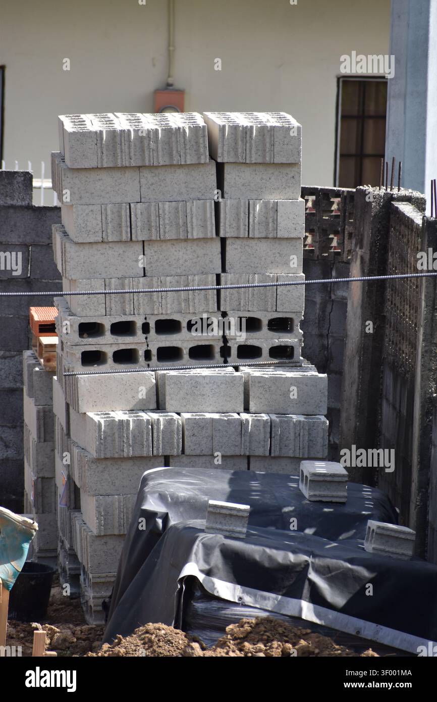 Una pila di blocchi di pareti in calcestruzzo cavo, noti anche come blocchi di cenere, impilati su pallet per l'uso edile. Foto Stock