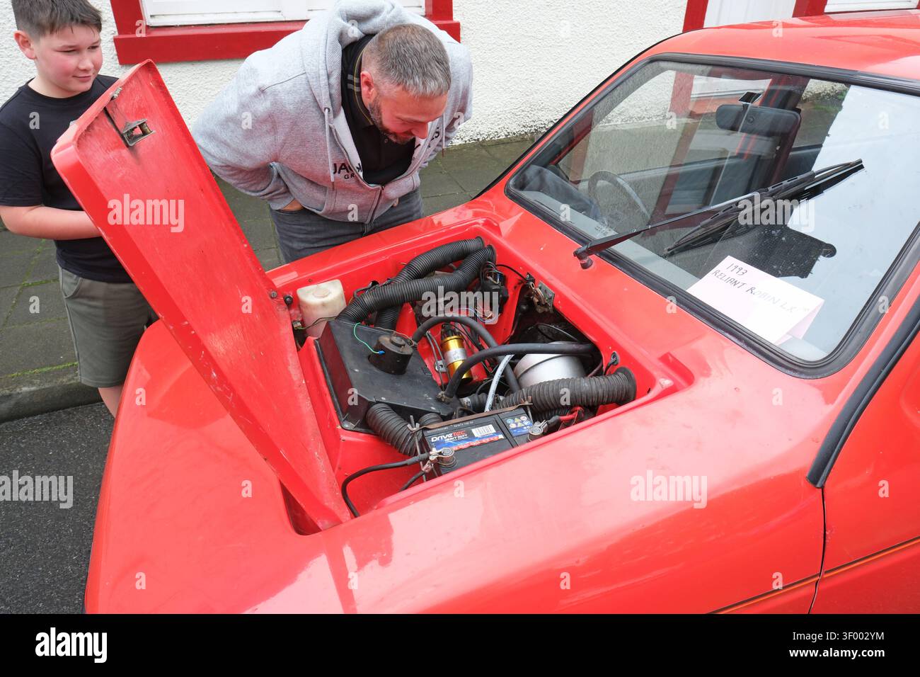 Un uomo esamina il motore di un'auto britannica a tre ruote Robin Reliant LX degli anni '1970 e '1980 al Wigtown Classic Car Show nel luglio 2026 Foto Stock