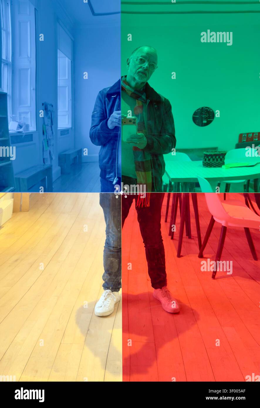 Uomo che scatta un selfie in uno spazio interno con quadranti sovrapposti di colore blu, verde, giallo e rosso Foto Stock