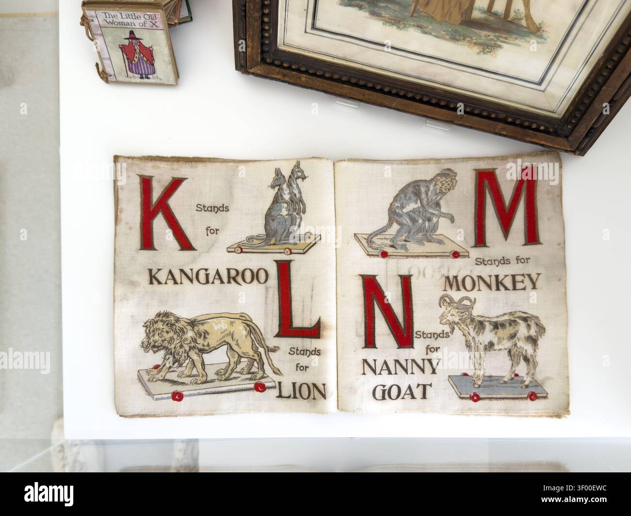 Un libro di alfabeto vintage aperto per bambini che mostra le lettere K, L, M e N con illustrazioni di un canguro, un leone, una scimmia e una capra tata Foto Stock