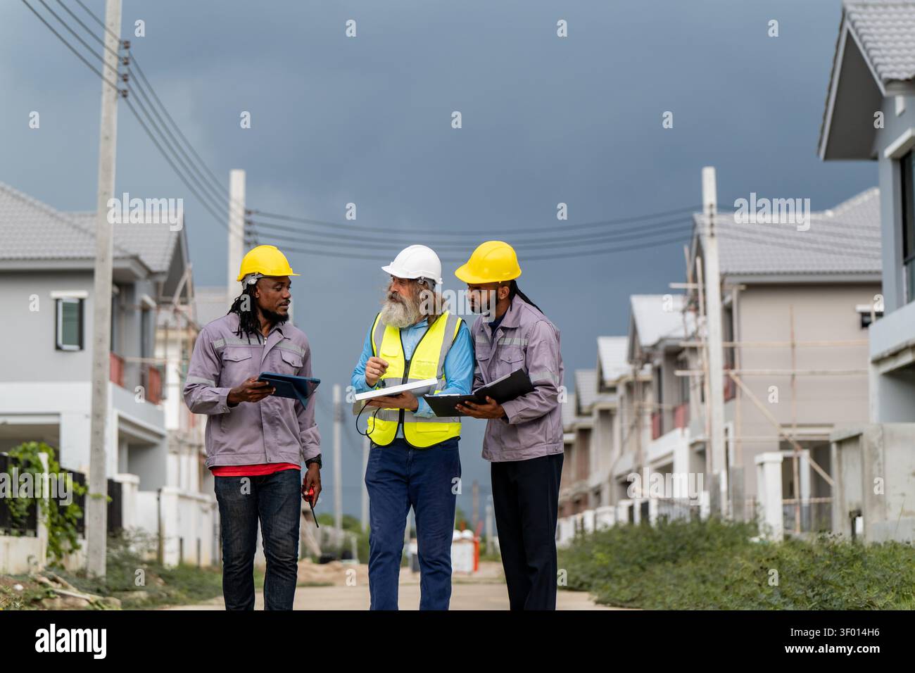 Gli ingegneri hanno discusso la preparazione per l'installazione di piccoli pannelli solari nelle aree di costruzione di villaggi residenziali per progetti di energia sostenibile e di improvvisazione Foto Stock