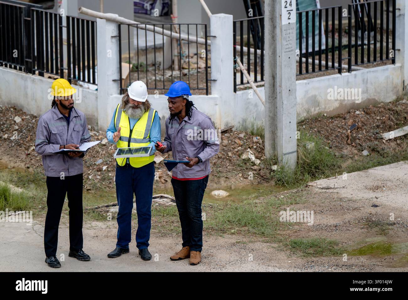 Gli ingegneri hanno discusso la preparazione per l'installazione di piccoli pannelli solari nelle aree di costruzione di villaggi residenziali per progetti di energia sostenibile e di improvvisazione Foto Stock