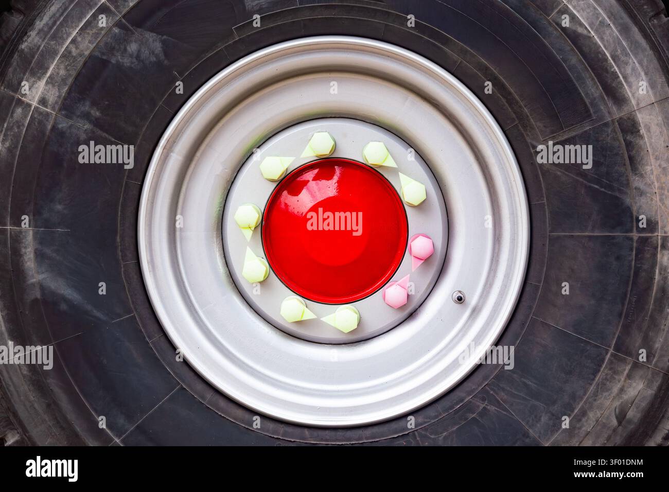Primo piano di una ruota per camion pesante con pneumatico nero cerchio argento mozzo rosso e indicatori di allentamento del dado di fissaggio in plastica colorata Foto Stock