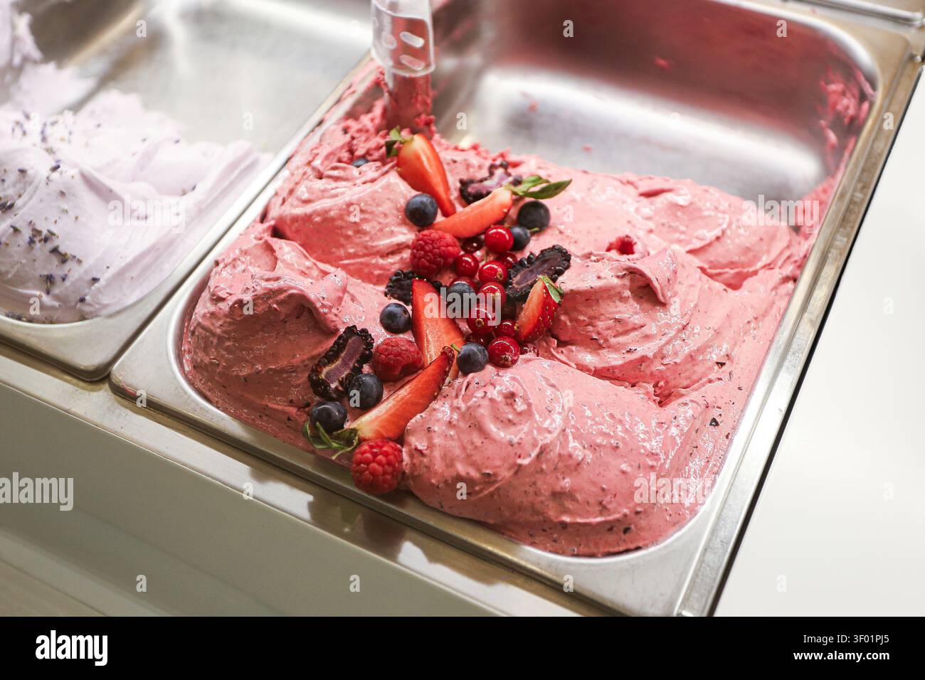 Gelato ai frutti di bosco e sorbetto alla frutta in contenitore di metallo. Sfondo di dessert congelato per rinfresco estivo, cibi dolci, sapori colorati e prelibatezze fredde. Foto Stock