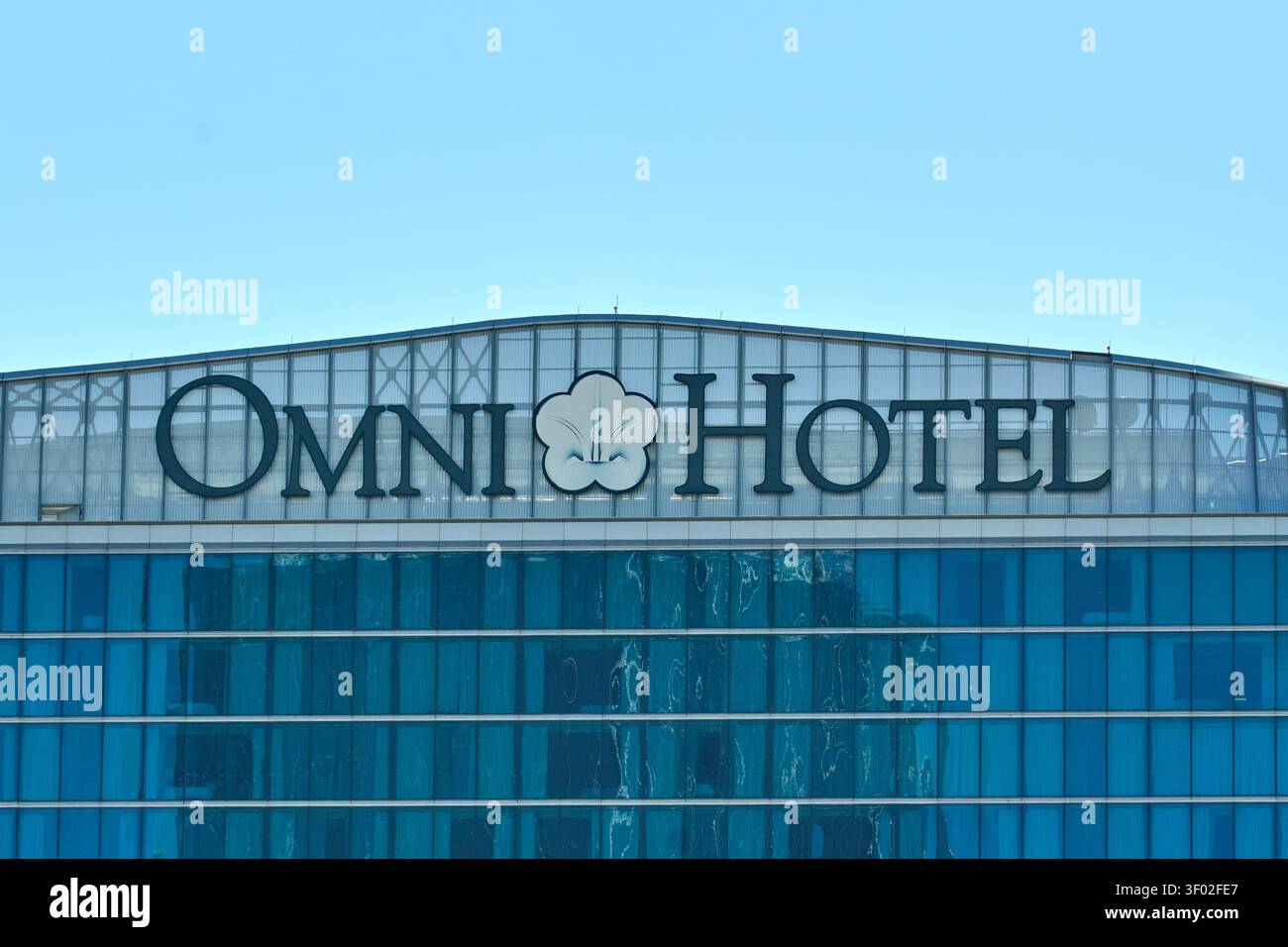 DALLAS, TX, USA - 16 FEBBRAIO 2024: Il logo dell'Omni Hotel è ben visibile sulla sommità di un moderno edificio in vetro. Il logo presenta un'audace blac Foto Stock