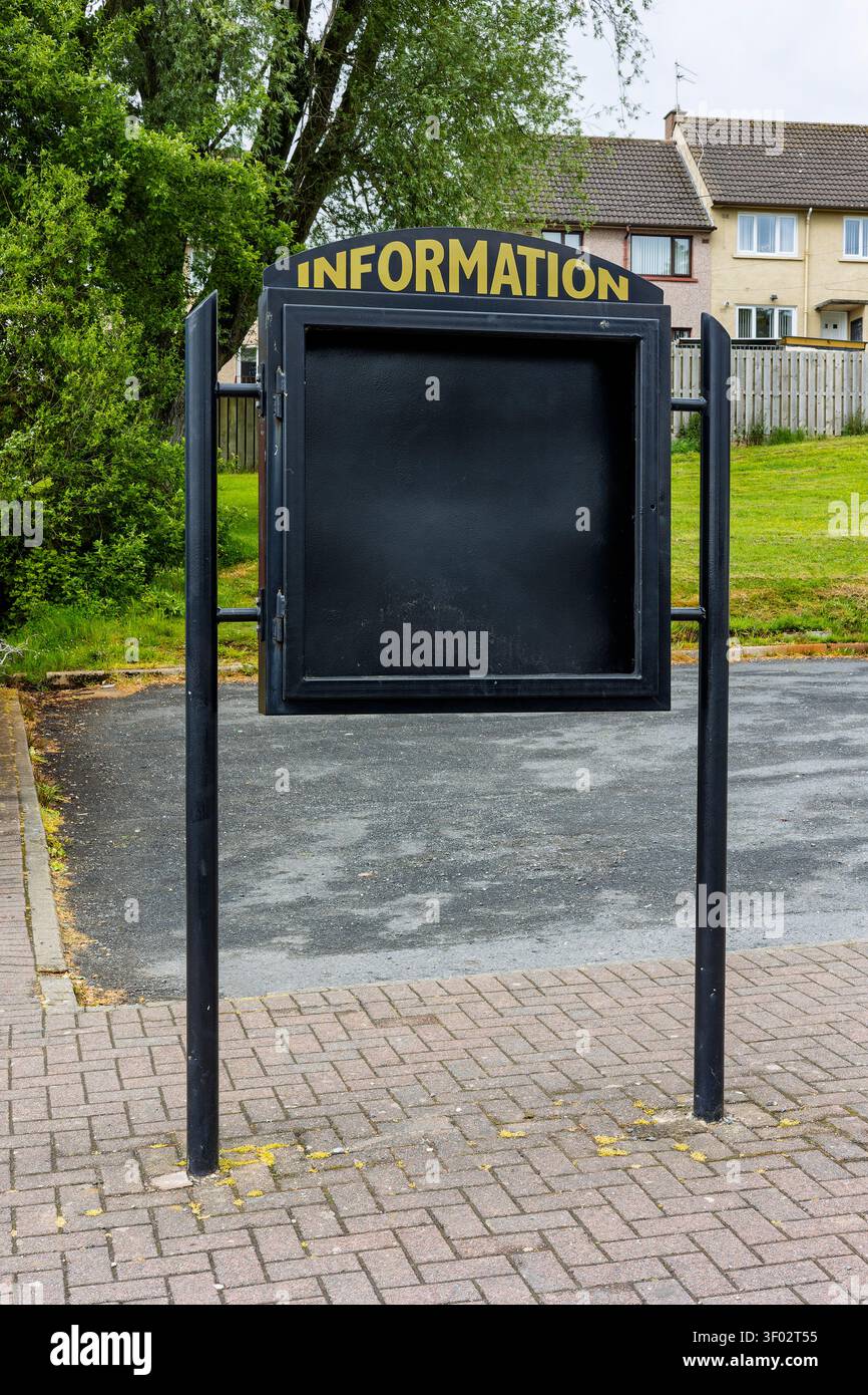 Una bacheca nera vuota con scritta dorata "INFORMATION" e la porta smaltata aperta, in piedi su un'area pavimentata in una residenza Foto Stock