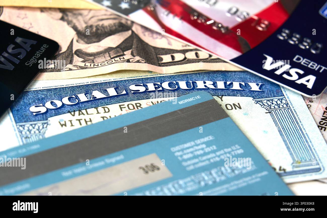 CARROLLTON, Texas, USA - 22 FEBBRAIO 2024: Un accordo di una carta di sicurezza sociale, più carte di credito e una banconota in dollari USA con un ritratto di Abra Foto Stock