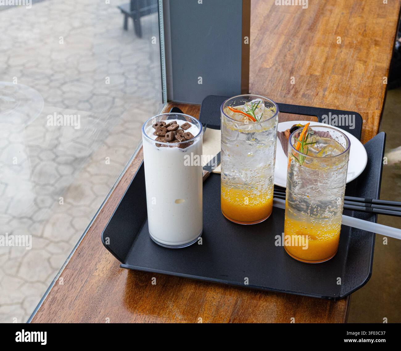 Rinfrescanti drink estivi al Cafe Table vicino alla finestra, tra cui scintillanti mocktail agli agrumi e Milkshake Foto Stock