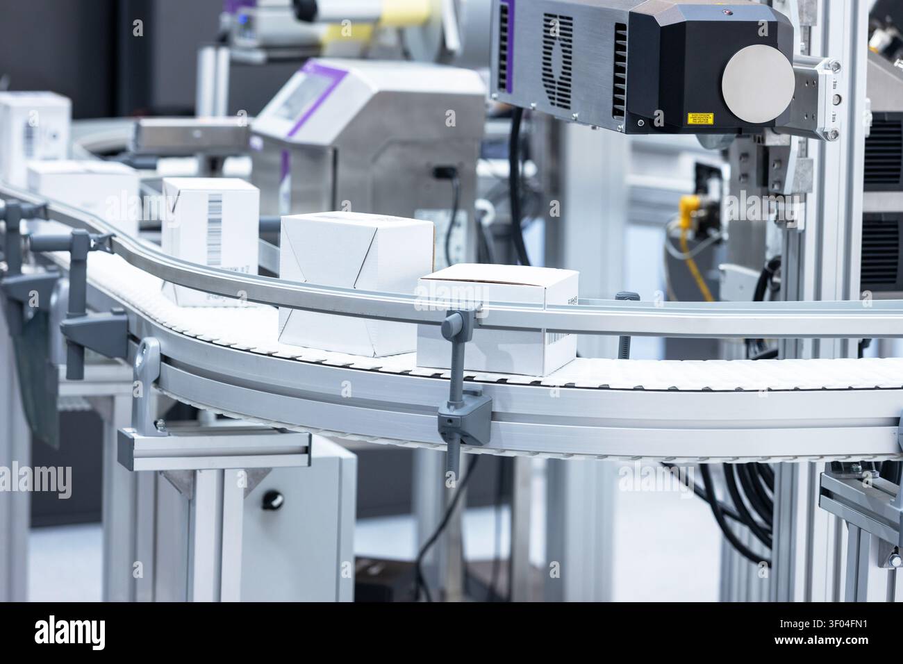 Sistema di convogliamento automatico per l'imballaggio con scansione di codici a barre e scatole di cartone in un moderno stabilimento di produzione industriale Foto Stock