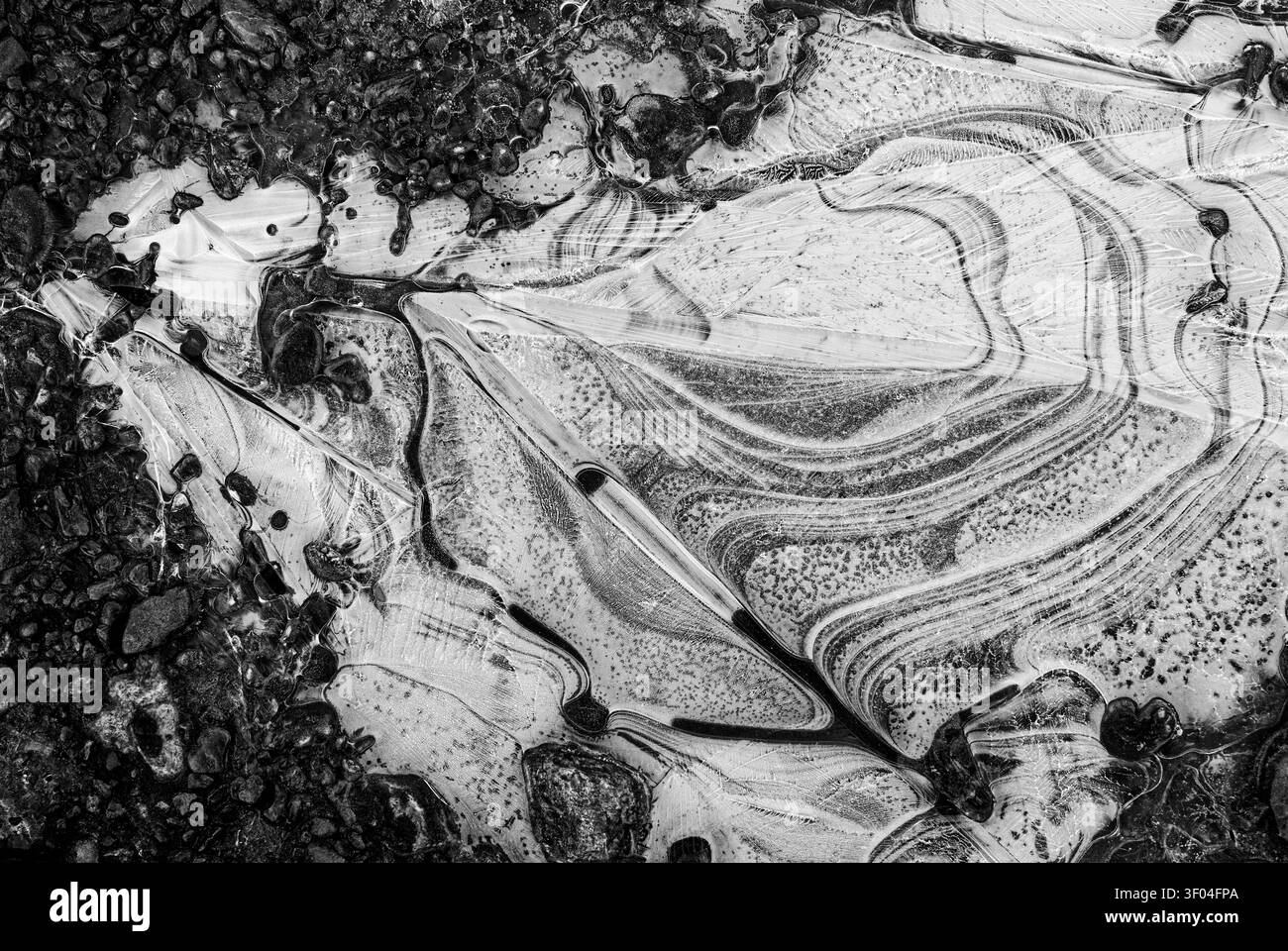Sfondo: risorsa grafica di arte naturale. Ghiaccio su una pozzanghera ghiacciata in bianco e nero a bassa luminosità. Foto Stock