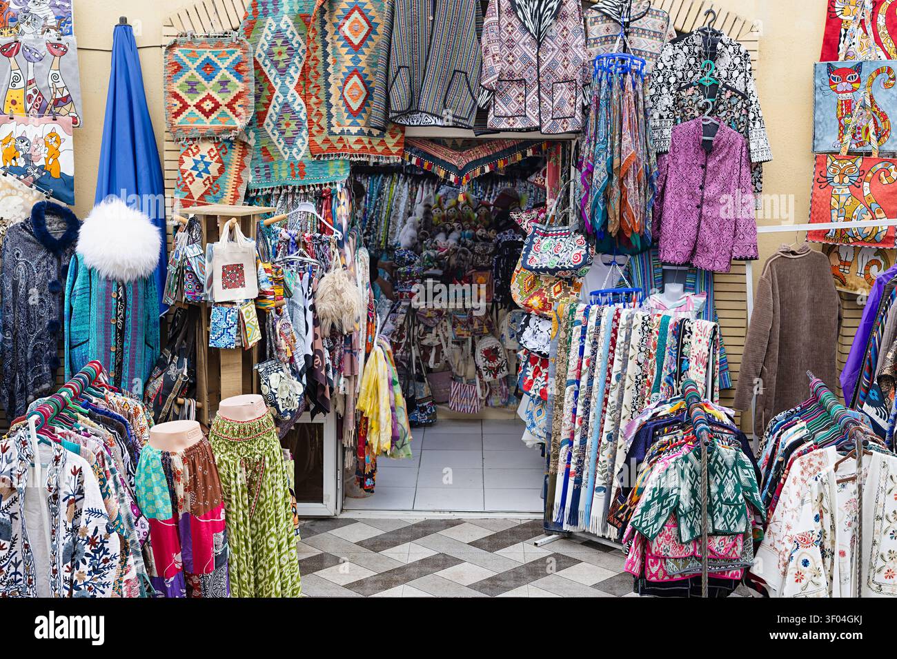 Colorato negozio di tessuti e souvenir al bazar Siab di Samarcanda traboccante di abbigliamento fatto a mano, tappeti kilim e artigianato. Ideale per viaggi e viaggi Foto Stock
