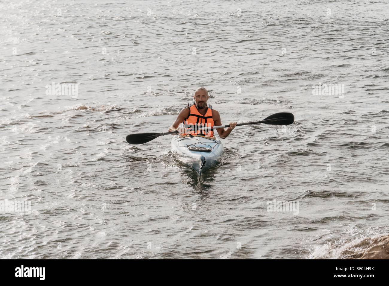 Kayak uomo sull'oceano pagaiando su una piccola barca in mare aperto durante una vacanza estiva attiva Foto Stock