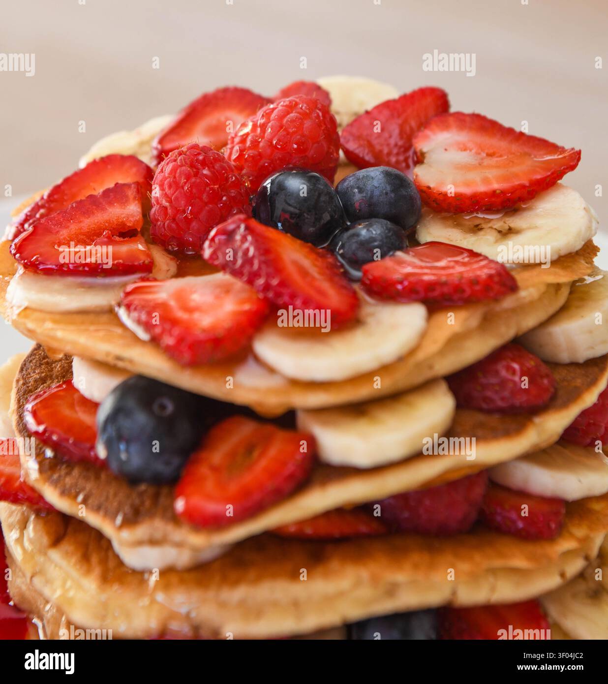 Pila di pancake con bacche fresche e banane a fette Foto Stock