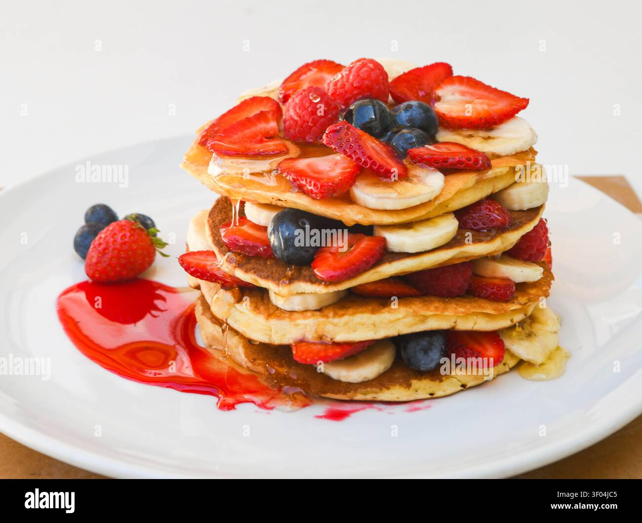 Pila di pancake con bacche fresche e banane a fette Foto Stock