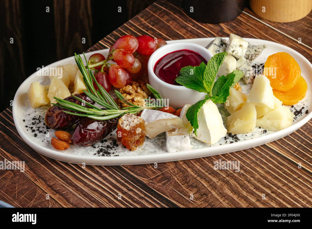 Tagliere di formaggi gourmet con frutta secca assortita e marmellata Foto Stock