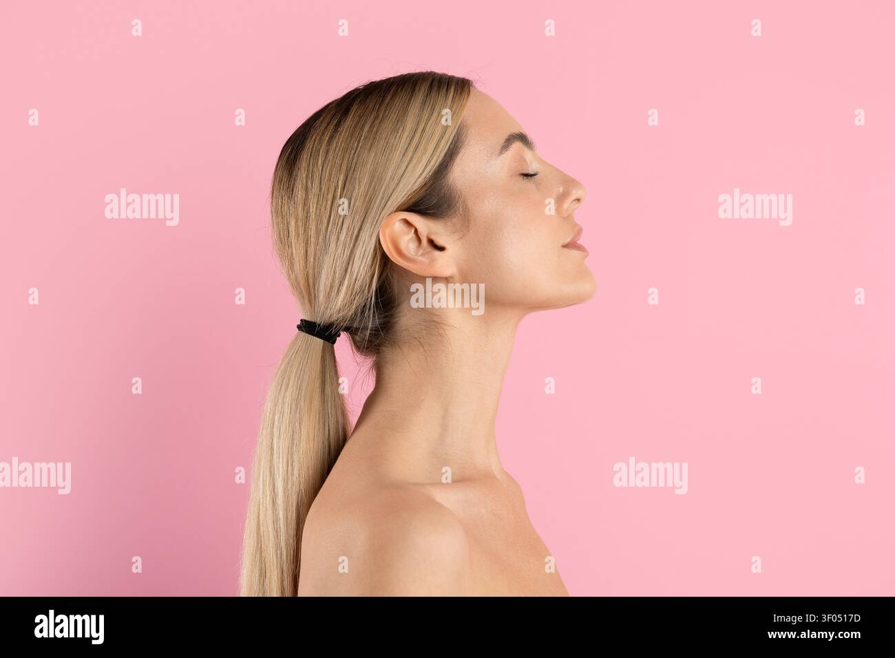 Giovane donna bella con gli occhi chiusi e la pelle liscia su sfondo rosa in studio Foto Stock