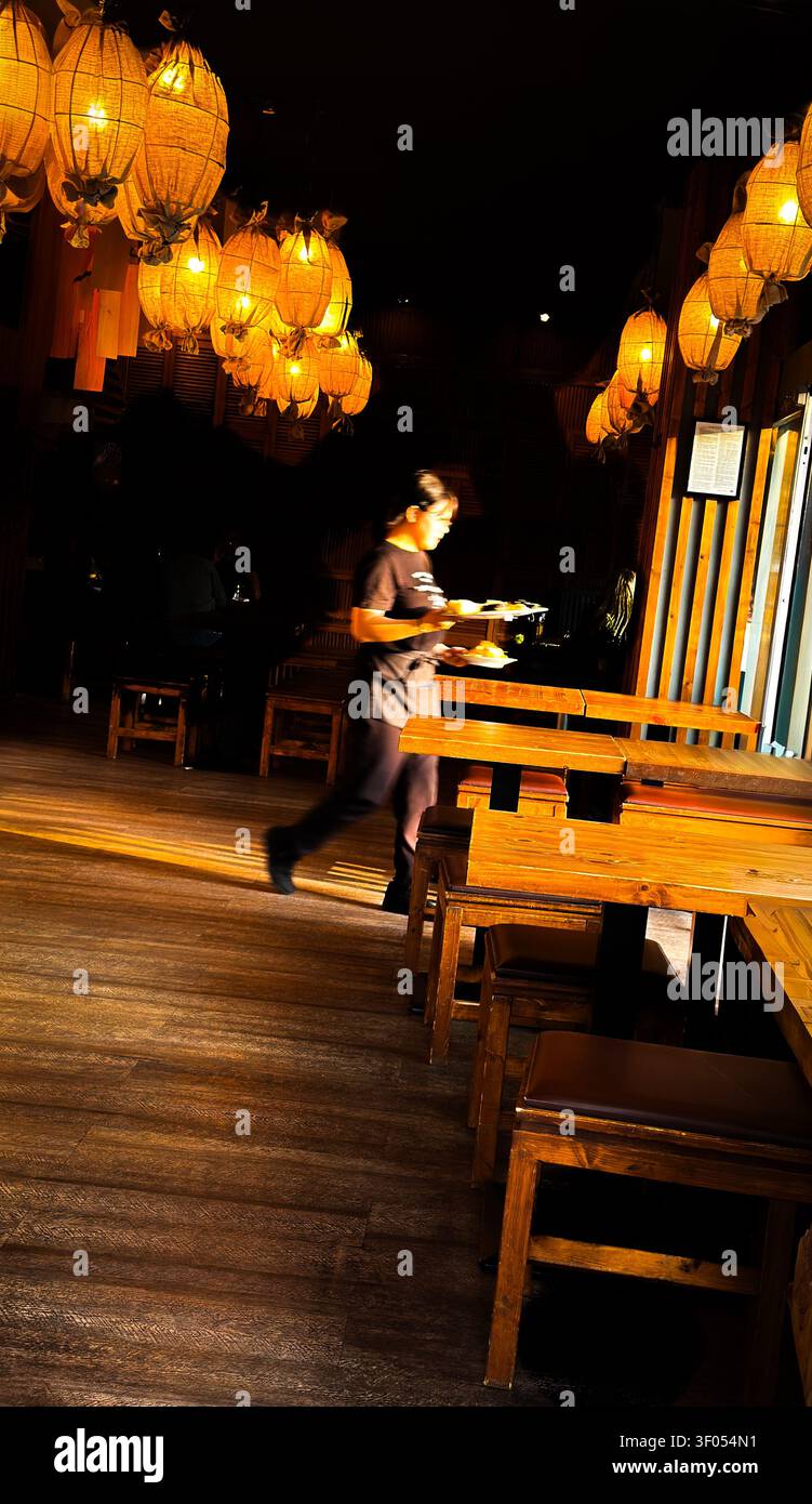 La cameriera serve piatti sotto lanterne luminose, ristorante asiatico strip, Kantstraße, Berlino, Germania Foto Stock