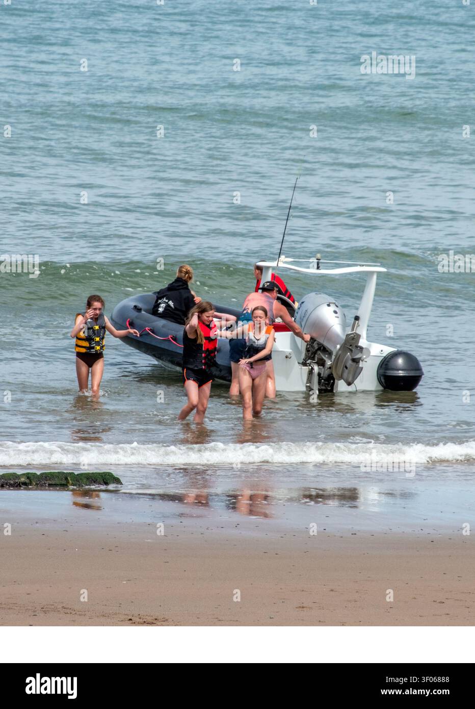 Turisti sbarcano da un giro in motoscafo a Llangrannog Foto Stock